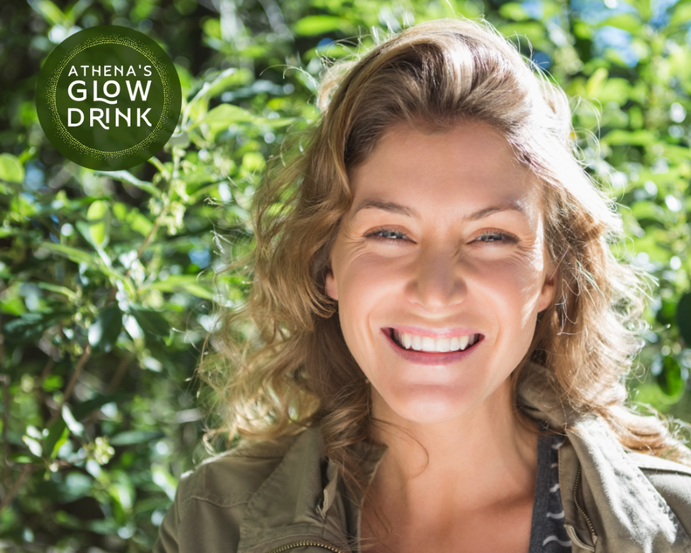 woman smiling outdoors with Athena's Glow logo