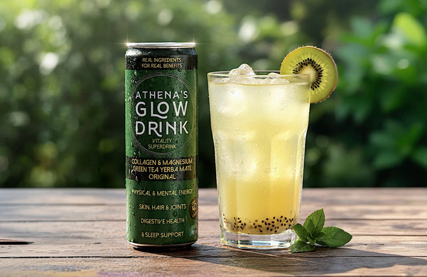 Athena's Glow Drink can and a glass of green juice with a kiwi on a wooden table outdoors.