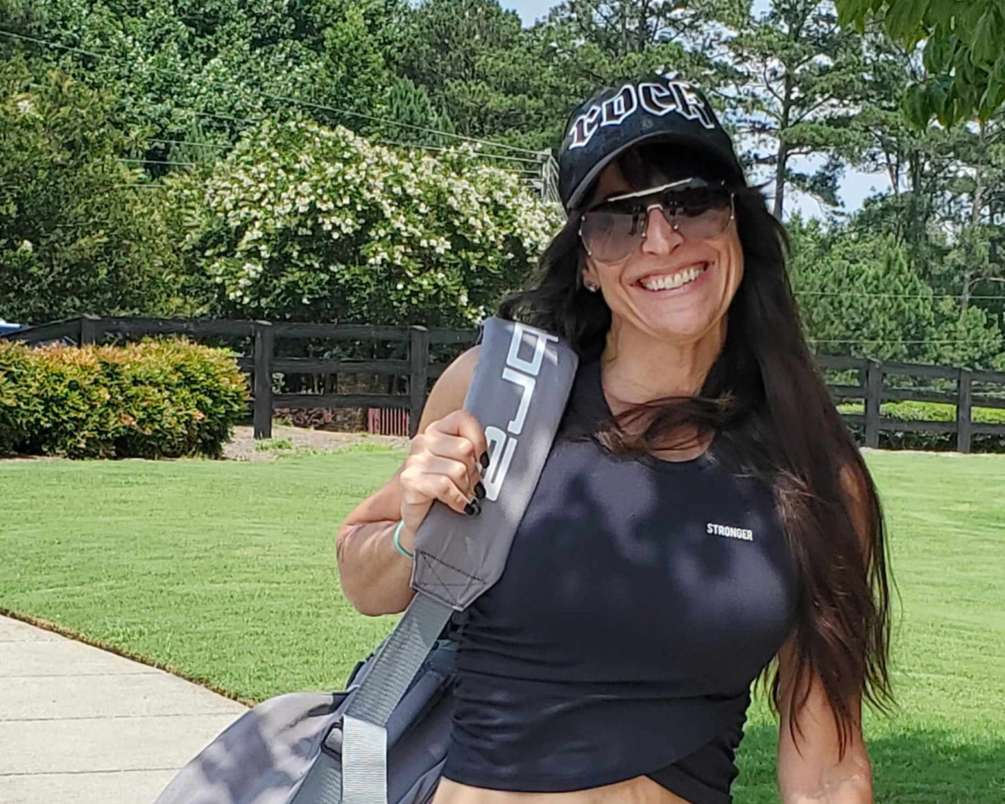 Woman holding a bag with a visible brand logo outdoors on a sunny day.