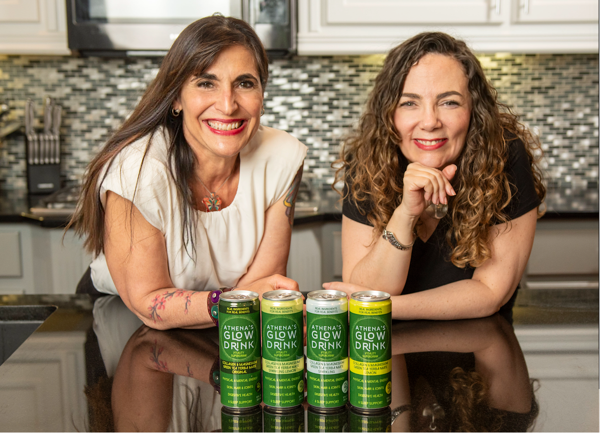 Athena's Glow founders in the kitchen with cans of Athena's Glow Drink' on the counter.